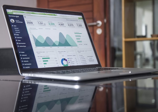 A picture of a laptop on a desk with some sort of analytics software opened up on it.